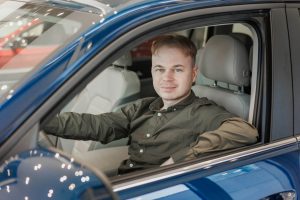 happy-man-is-sitting-in-a-blue-car-in-a-car-dealership-a-man-buys-a-car-at-a-car-dealership.jpg