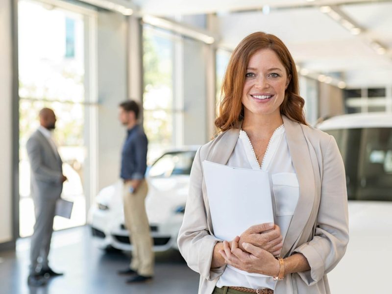 satisfied-saleswoman-in-car-dealership.jpg